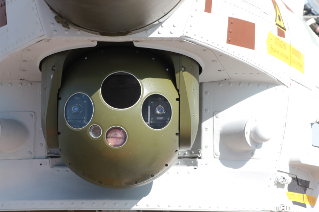 Nahaufnahme eines Militärfahrzeugs mit einer runden, grün-weißen Rakete, die seitlich auf einem Metallrahmen montiert ist.