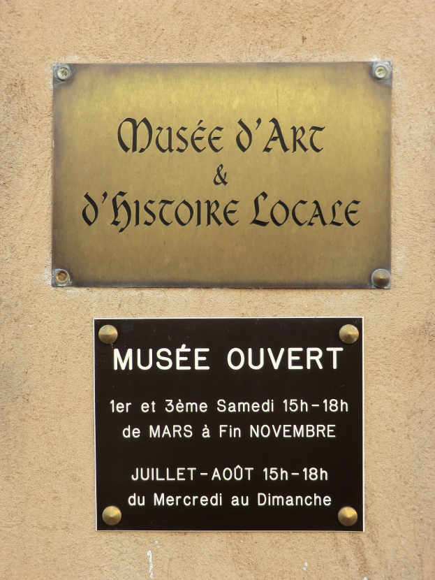 Metallplatte an der Seite eines Gebäudes mit der Aufschrift "Musee d'Art und D'Histoire Locale" mit Text über das Museum.