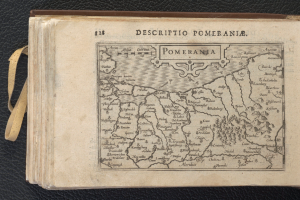 Ein altes Buch mit einer detaillierten Karte von Pommern, die verschiedene Städte und Ortschaften zeigt, liegt auf einer schwarzen Oberfläche.