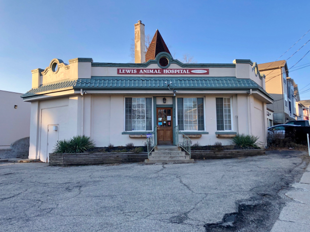 Außenansicht der Lewis Animal Hospital in San Francisco, mit einem Fenster- und Tür-Building, umgeben von Pflanzen und Treppen mit Geländern, einem Schild an einem Pfosten, parkenden Fahrzeugen in der Nähe, sichtbarem Himmel und Oberleitungen.