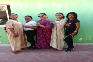 Eine Gruppe von Frauen, die vor einer grünen Wand mit einem Fenster auf der linken Seite stehen und an einer Internationalen Frauentagsveranstaltung teilnehmen.