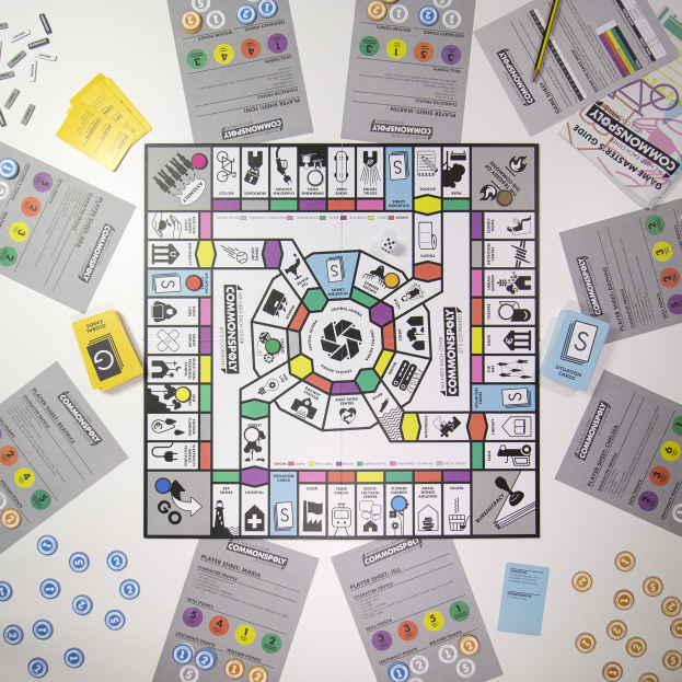 Ein Monopoly-Brettspiel auf einem Tisch mit Spielkarten, Papieren und einem Bleistift, der um das Spielbrett und seine Teile verstreut ist.