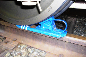 Ein Nahaufnahme eines Zugrades auf einer Schiene mit einer blauen Bremse, umgeben von Steinen.