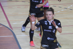 Eine Gruppe von Frauen in Sportuniformen, die Volleyball auf einem Platz spielen.