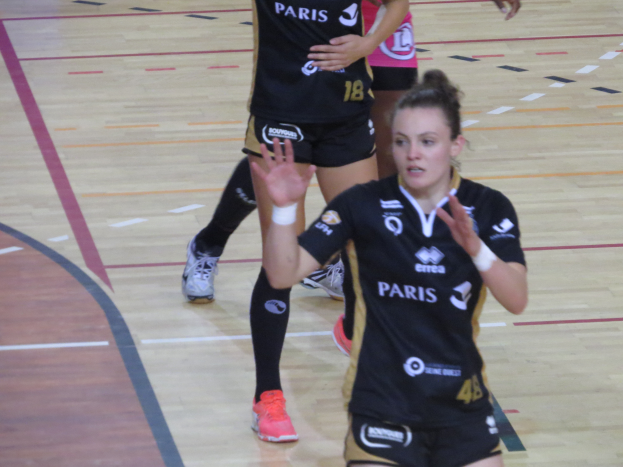 Eine Gruppe von Frauen in Sportuniformen, die Volleyball auf einem Platz spielen.
