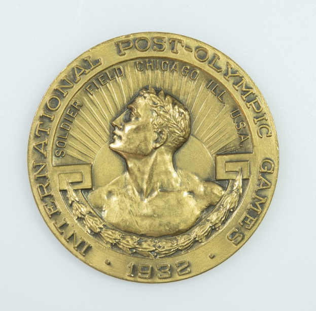 Eine Goldmedaille mit der Inschrift "Internationale Post-Olympische Spiele" auf einem weißen Hintergrund.