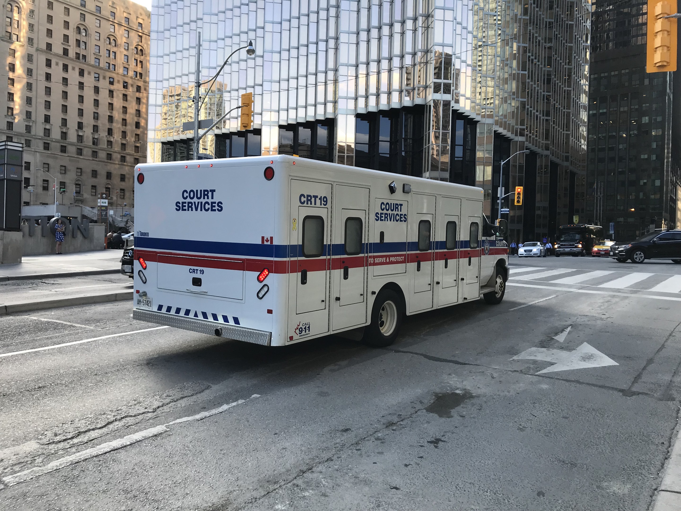Ambulanz auf einer Stadtstra├če geparkt, umgeben von hohen Geb├Ąuden, Stadtinfrastruktur und Passanten mit dem Himmel im Hintergrund.
