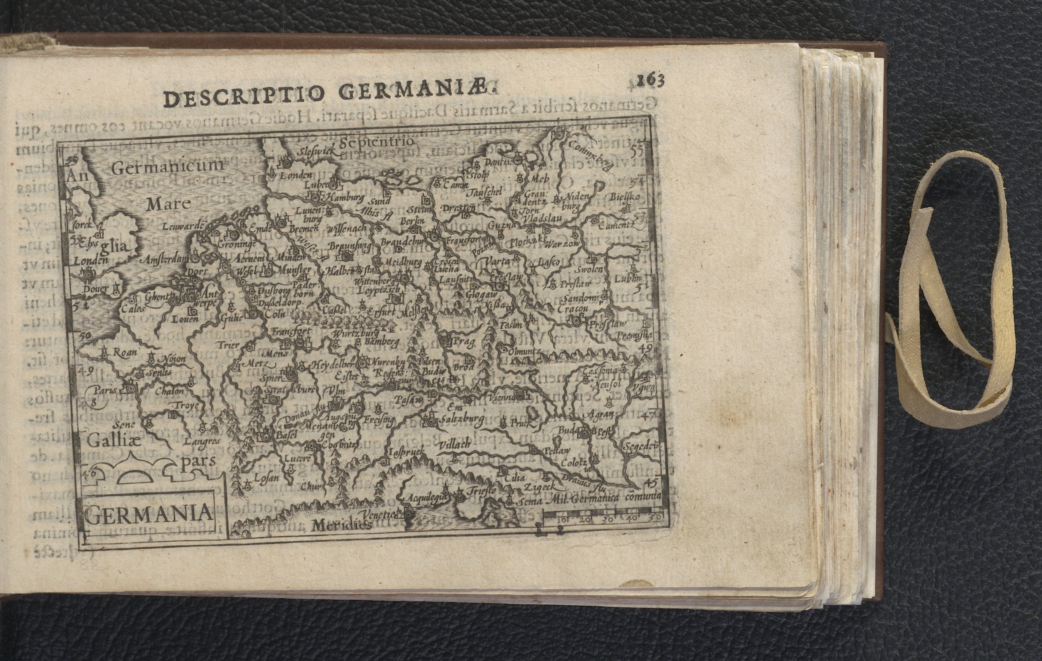 Ein aufgeschlagenes Buch mit einer Deutschlandkarte auf einer schwarzen Oberfläche, das eine Seite mit Text und einer Karte zeigt.