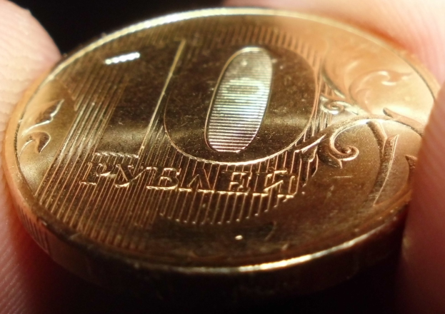 Eine Person mit einer Goldmünze in der Hand vor einem dunklen Hintergrund.