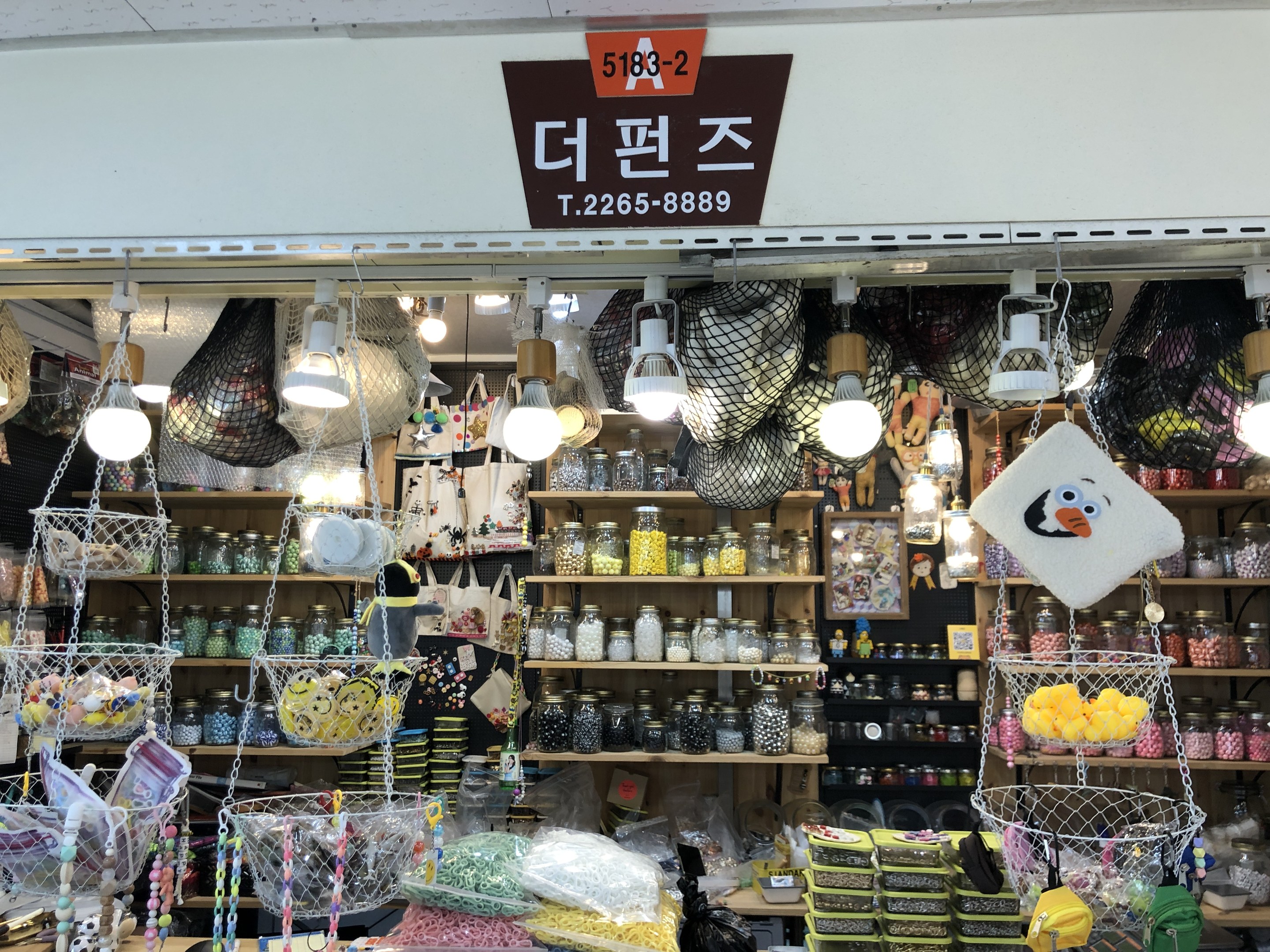 Ein Geschäft mit verschiedenen Gegenständen wie Körben, Lampen, Flaschen und Spielzeugen auf Regalen, mit einem Schild oben, das es als eines der besten koreanischen Geschäfte in Seoul ausweist.