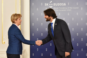 Bundeskanzlerin Angela Merkel und Bundeskanzler Joachim Gauck schütteln sich die Hände vor einem Banner mit der Aufschrift "EU-Gipfel", während sie freundlich lächeln.