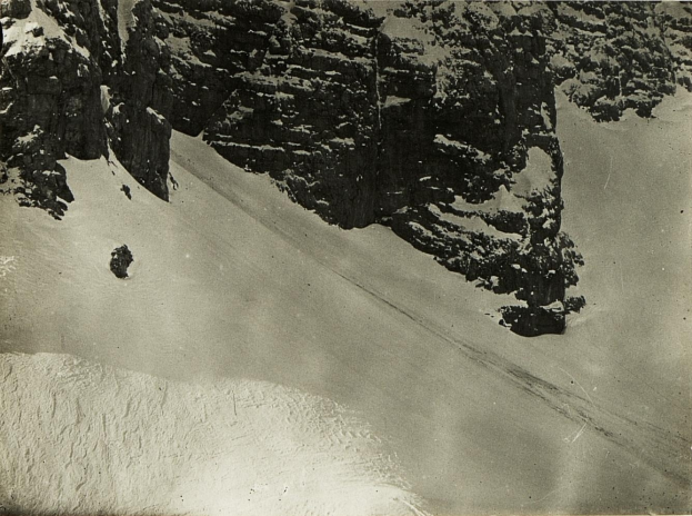 Eine Person, die eine schneebedeckte Bergabhang hinabski fährt, umgeben von schneebedeckten Hügeln, mit Text am unteren Bildrand.