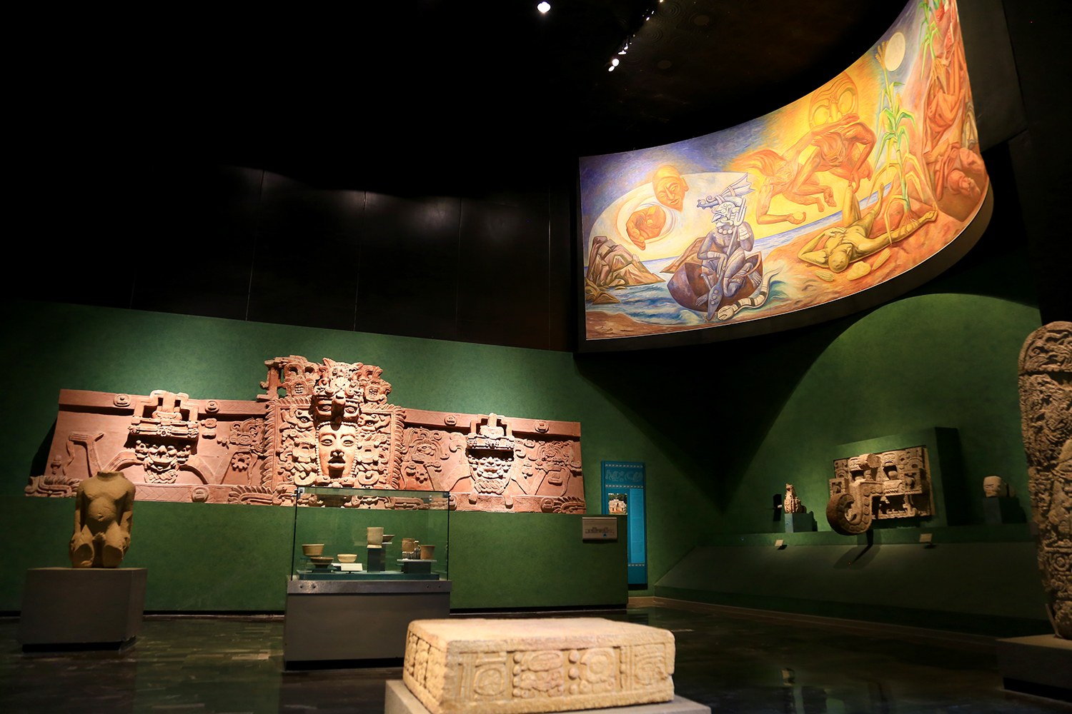 Ausstellung verschiedener Artefakte im Mexiko-Stadt-Museum der Anthropologie, darunter Skulpturen, Tischobjekte, eine Texttafel, eine Wandmalerei und Deckenbeleuchtung.