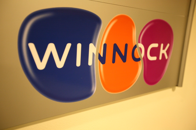 Buntes "Winnock"-Schild an einer Wand angebracht, das einen Aktienmarkt anzeigt.
