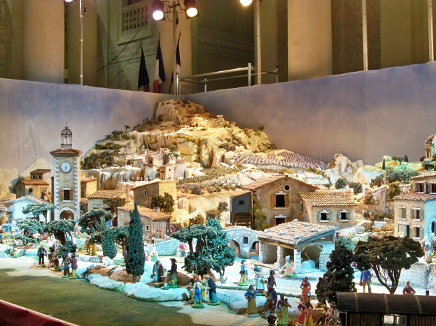Ein detailliertes Modell einer Krippe in einem Museum, das Figuren, Strukturen und beleuchtete Elemente zu einer festlichen Darstellung zusammenführt.