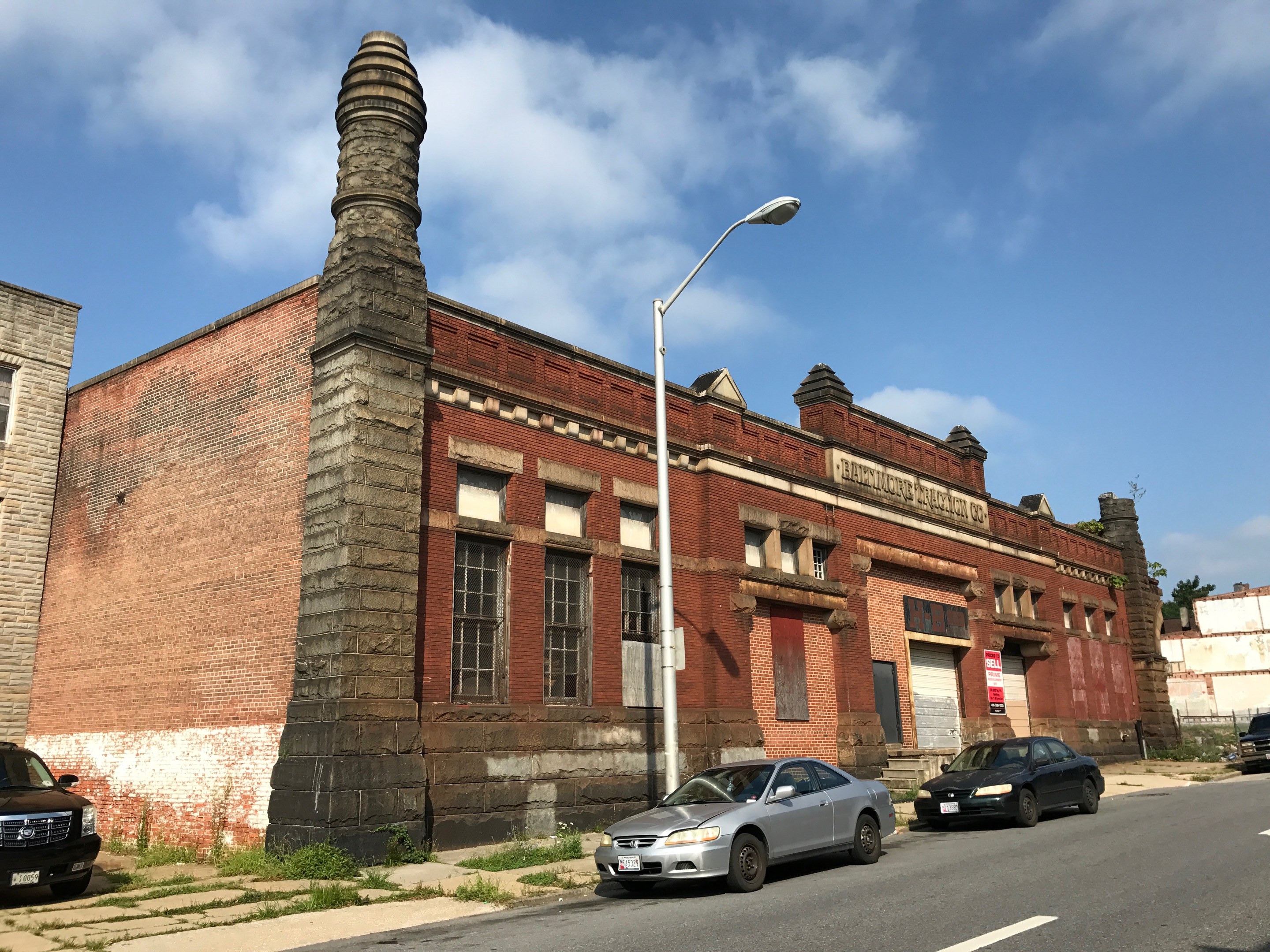 Außenansicht einer ehemaligen Feuerwache in St. Louis, ein altes Backsteingebäude mit einem Seitenkamin, umgeben von Straßeninfrastruktur und Fahrzeugen unter einem bewölkten Himmel.