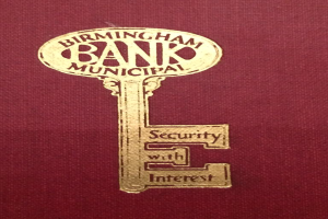Ein rotes Buch mit einem goldenen Schlüssel darauf, beschriftet mit "Birmingham Bank Municipal Security with Interest."